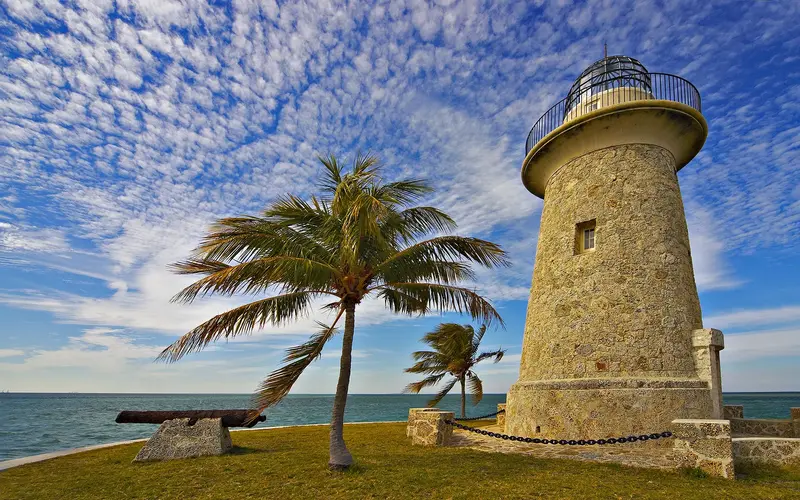 Boca Chita lighthouse next to a cannon and palm trees